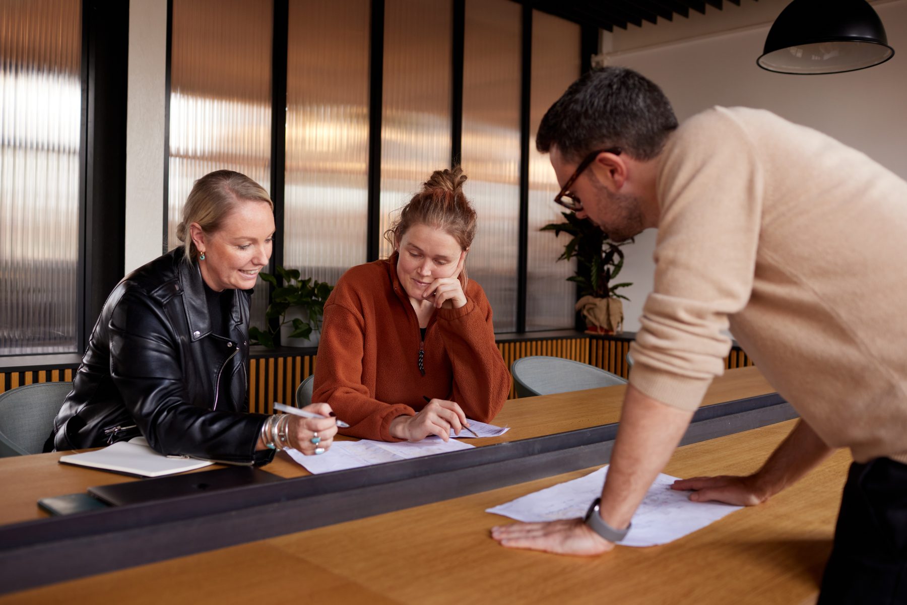 People sat around a meeting room table reading sheets of paper