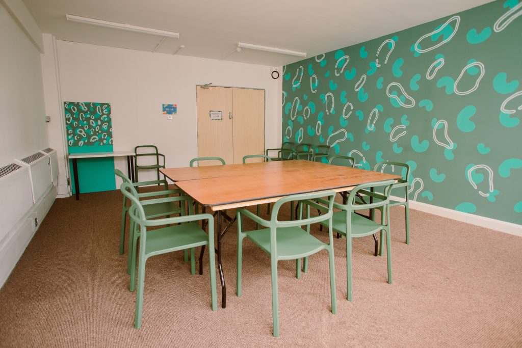 A meeting room with a green theme. Green walls, green chairs