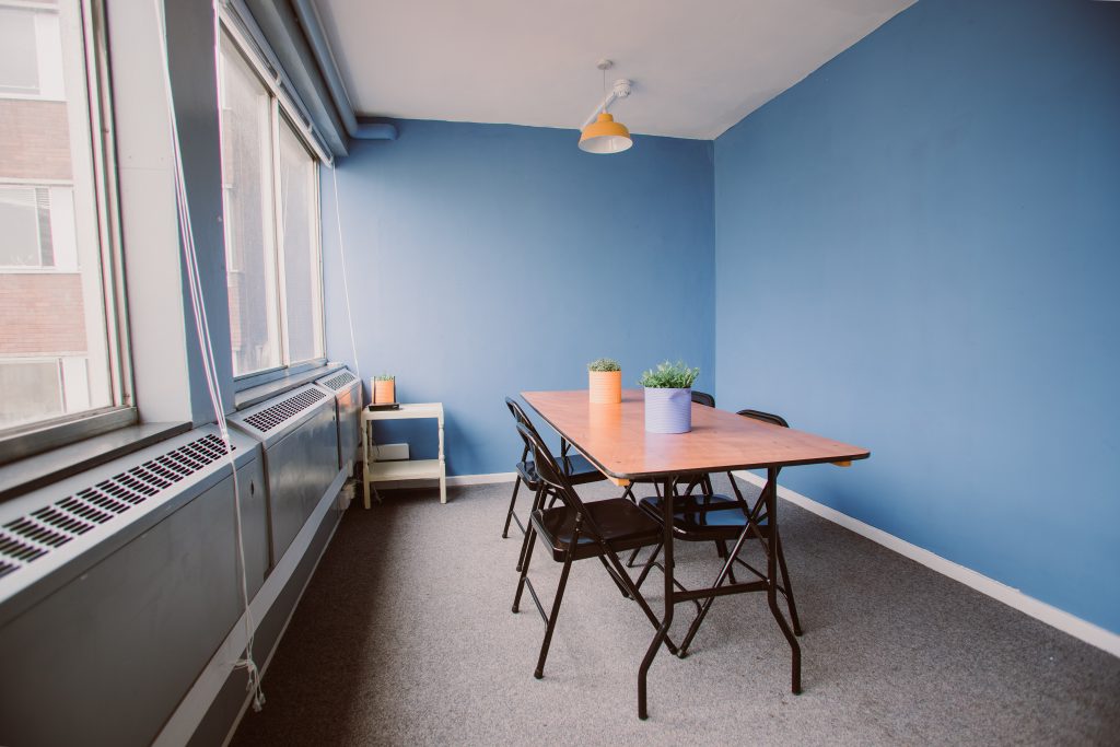 A small meeting room with blue walls and a table and chairs