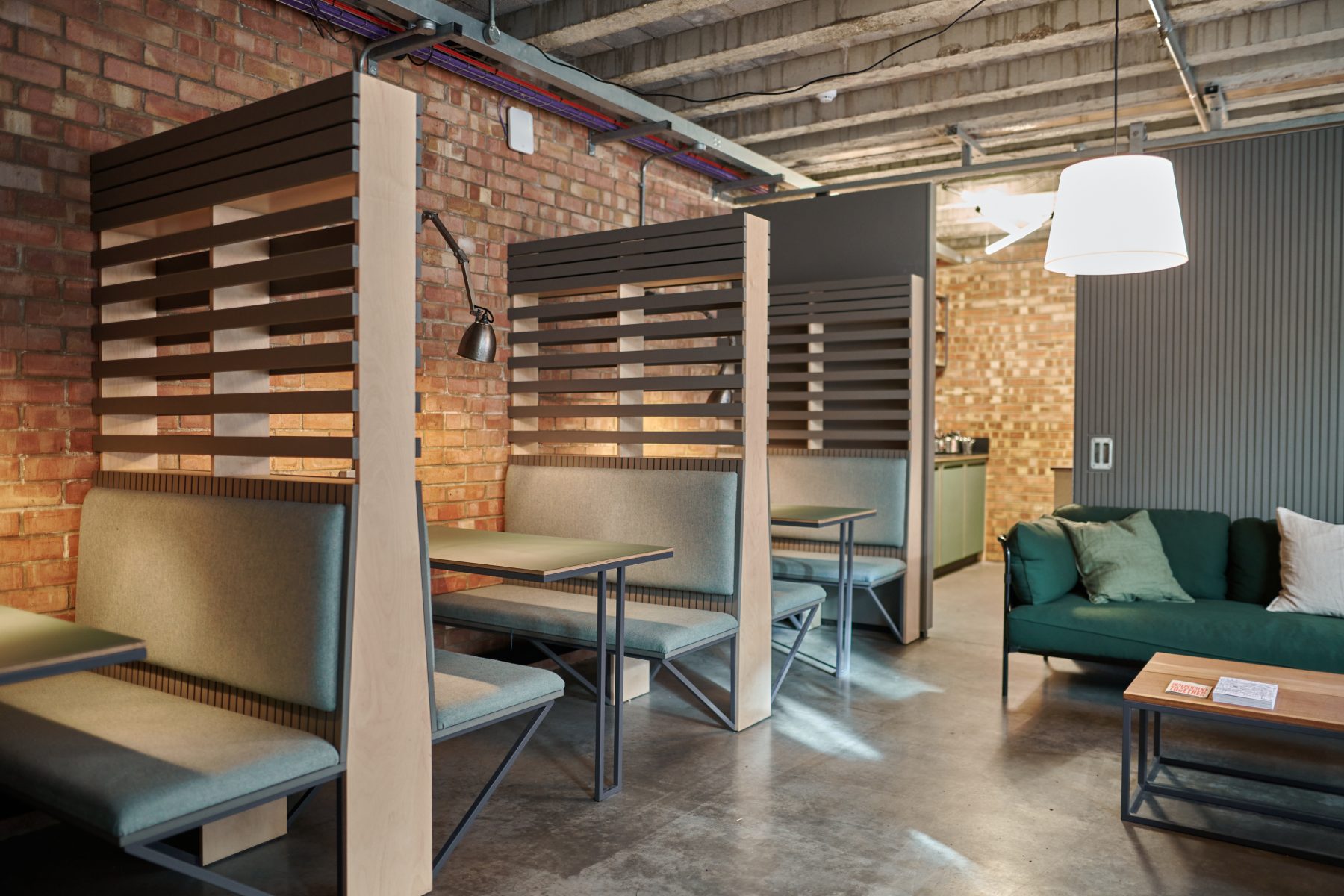 A cafe-style space with concrete floor and upholstered booth seating.